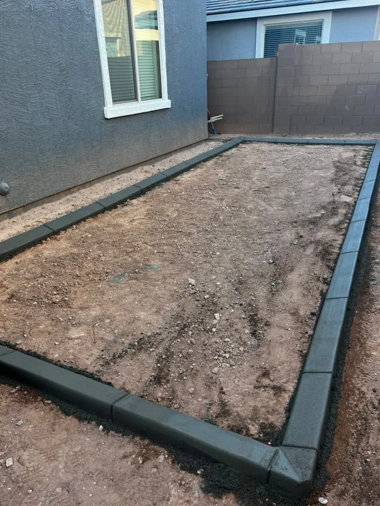 Concrete curbing poured around a side yard, graded flat and ready for turf or rock.
